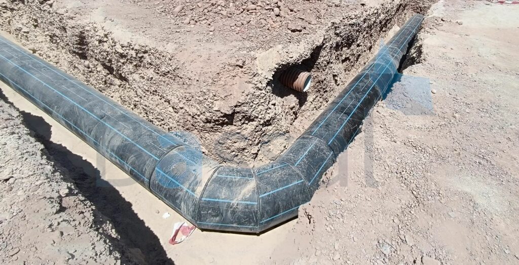 Trench with HDPE pipe elbow formed from sections joined by electrofusion