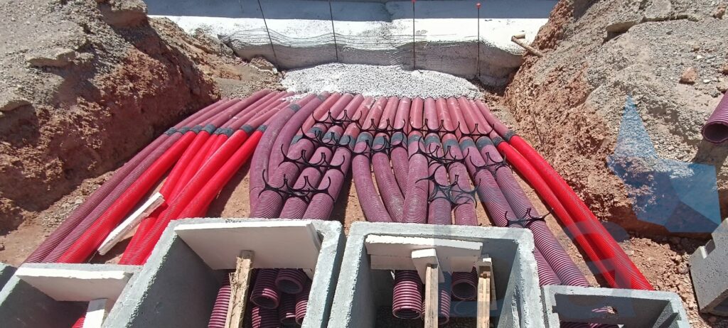 Electrical conduits crossing a retaining wall and reaching their manholes.